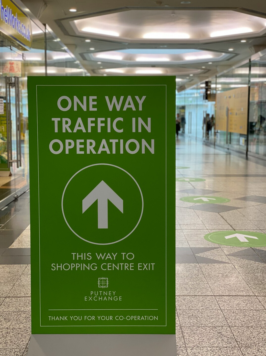 Store greeter standing near entrance flow-control signage
